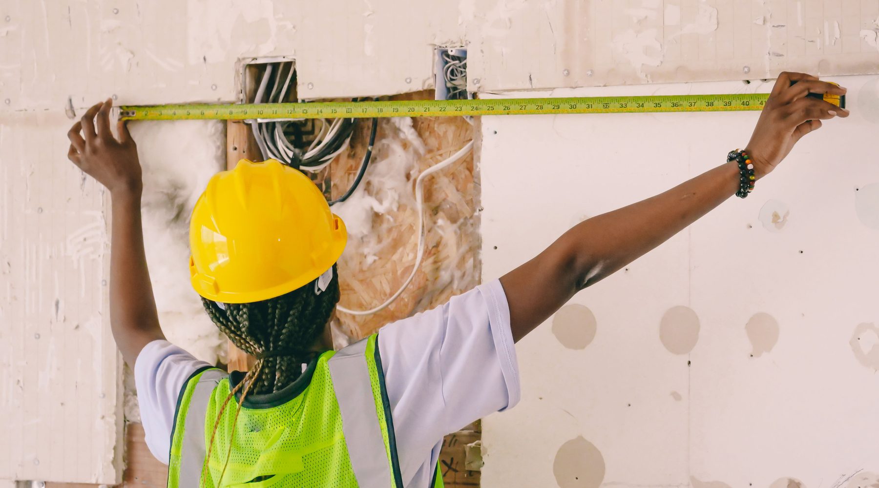Construction worker measuring an open interior wall