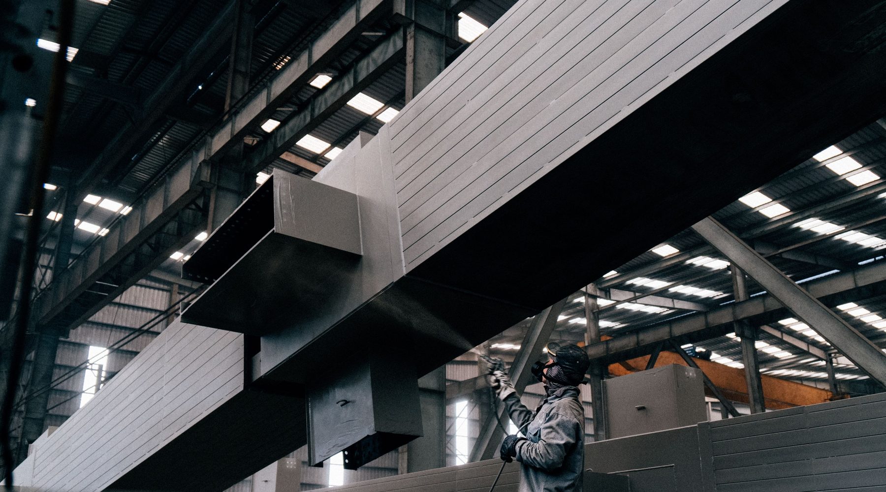 Worker applying a protective coating to structural steel